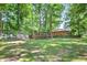 Lush backyard with mature trees, large lawn, and greenhouse at 686 Hillwood Ct, Dacula, GA 30019