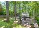Secluded backyard with stone patio, greenhouse, and mature trees offers tranquility and space for outdoor living at 686 Hillwood Ct, Dacula, GA 30019