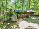 Secluded backyard featuring a greenhouse, deck, patio, and lush landscaping amidst mature trees at 686 Hillwood Ct, Dacula, GA 30019