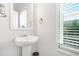 Clean powder room with a pedestal sink, decorative mirror, and window with blinds at 3641 Princeton Ave, Atlanta, GA 30337