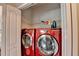 Convenient laundry area featuring modern red front-load washer and dryer units, complete with storage shelves at 510 Elgaen Ct, Roswell, GA 30075