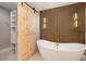 Modern bathroom with white free standing tub and a sliding wood door to the walk-in closet at 9025 Huntcliff Trce, Atlanta, GA 30350