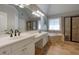 Well-lit bathroom featuring dual sinks, soaking tub, walk-in shower, and tile floors at 998 Poplar Mill Ct, Buford, GA 30518