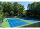 Full tennis court with new blue and green surface, black chain link fence, and green benches at 998 Poplar Mill Ct, Buford, GA 30518
