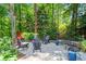 Stone patio featuring comfortable chairs, string lights, red firepit, and lush landscaping at 4686 Buckskin Sw Trl, Lilburn, GA 30047