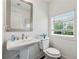 Bright powder room featuring pedestal sink, large mirror and a window letting in natural light at 2161 Colvin Ct, Atlanta, GA 30318