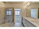 Bathroom featuring double vanity, large mirror, walk-in shower with gray tiles and a view to the bedroom at 3879 Glenview Club Ln, Duluth, GA 30097