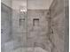 Walk-in shower featuring gray stone-look tiles, rainfall shower head, and a built-in niche for toiletries at 3879 Glenview Club Ln, Duluth, GA 30097