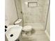 Bathroom with a toilet, sink, and a shower featuring marble-look tile and a built-in niche at 559 Allgood Rd, Stone Mountain, GA 30083