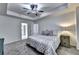 Bright bedroom featuring a tray ceiling, ceiling fan, plush carpet, and natural light from the windows at 6520 Fairfield Trce, Suwanee, GA 30024