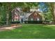 Beautiful home with a lush green lawn, brick accents, blue shutters, and mature trees at 6520 Fairfield Trce, Suwanee, GA 30024