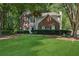Traditional home with manicured lawn, brick facade, contrasting shutters, and mature trees at 6520 Fairfield Trce, Suwanee, GA 30024