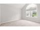 An empty bedroom with neutral carpet features a high ceiling and a large window overlooking the yard at 1890 Owens Trl, Rex, GA 30273