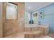 Elegant bathroom featuring a marble tiled shower, jetted tub and natural light from shuttered windows at 1961 Luke Edwards Rd, Dacula, GA 30019