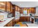 Well-equipped kitchen boasts cherry wood cabinets, sleek countertops, and stainless steel appliances at 1961 Luke Edwards Rd, Dacula, GA 30019