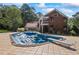 Backyard in-ground pool with diving board next to a brick home and lush greenery at 1961 Luke Edwards Rd, Dacula, GA 30019