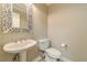 Charming powder room featuring a pedestal sink with an ornate mirror and a modern toilet at 4120 Grady Smith Rd, Loganville, GA 30052