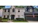 Front elevation showcasing a white-brick home with a black two-car garage and a manicured front yard at 4385 Pinehollow Court Ct, Alpharetta, GA 30022