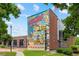 Exterior shot of a building with a colorful mural and the American flag waving above at 5139 Peachtree Road, Chamblee, GA 30341