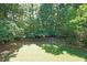 A lush green backyard enclosed by a wooden fence, surrounded by mature trees at 5176 Shotwell St, Woodstock, GA 30188