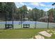 A fenced tennis court offers a recreational space with benches, set against a backdrop of lush greenery and blue sky at 5176 Shotwell St, Woodstock, GA 30188