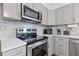 Kitchen with stainless steel appliances, grey cabinetry and light countertops, adding modern flair at 4691 Shumate Dr, Stone Mountain, GA 30083