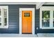 Close-up of a vibrant orange front door with glass paneling and white trim, complemented by windows and siding at 943 Rose Sw Cir, Atlanta, GA 30310