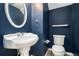 Stylish powder room featuring navy walls, a pedestal sink, and modern fixtures at 139 W Oaks Pl, Woodstock, GA 30188