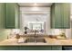 Close-up view of the kitchen sink with granite countertops and sage cabinetry and a view to the living room at 273 12Th Ne St # 111, Atlanta, GA 30309