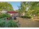 Serene backyard with gravel patio, a red umbrella, lush greenery and mature trees, perfect for outdoor enjoyment at 4442 Academy St, Acworth, GA 30101