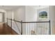 Hallway with hardwood floors, white railings, and a window offering natural light and view of the outdoor scenery at 135 Emerald Ln, Roswell, GA 30075