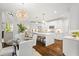 Open kitchen and dining area featuring white cabinetry, stainless steel appliances, hardwood floors, and stylish lighting at 135 Emerald Ln, Roswell, GA 30075