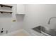 A simple laundry room with a deep utility sink, floating shelves and tile flooring at 135 Emerald Ln, Roswell, GA 30075
