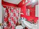 Bold bathroom with a red accent wall featuring a shower with curtain, toilet, and sink at 1876 Madrona Street Nw St, Atlanta, GA 30318