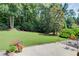Beautifully landscaped backyard featuring lush lawn, mature trees, and a stone patio at 3030 Larkspur Ct, Cumming, GA 30041