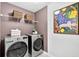 Modern laundry room featuring front-loading washer/dryer, storage shelves, and decorative wall art at 165 Winner St, Acworth, GA 30102