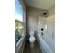 Well-lit bathroom featuring a bathtub with shower, a toilet, and a window for natural light at 2147 Saint Albans Pl, Buford, GA 30519
