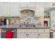 Renovated kitchen with a stainless steel sink, granite countertops, subway tile backsplash, and white cabinetry at 672 Victorian Cir, Dallas, GA 30157