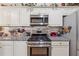 Modern kitchen boasts stainless steel appliances, granite countertops, mosaic backsplash, and white cabinets at 672 Victorian Cir, Dallas, GA 30157