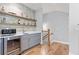 Modern wet bar with gray cabinets, open shelving, tile backsplash, stainless steel sink and a beverage cooler at 4486 Huffman Drive Ne Dr, Roswell, GA 30075
