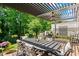 Relaxing outdoor patio with a pergola, ceiling fan, dining table, grill, and lush greenery at 4486 Huffman Drive Ne Dr, Roswell, GA 30075