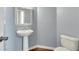 Cozy powder room with a pedestal sink, mirror, and a toilet in a blue-walled space at 213 Roseman Way, Woodstock, GA 30188