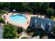 Aerial view of a community pool and clubhouse surrounded by trees and lush landscaping at 213 Roseman Way, Woodstock, GA 30188