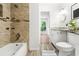 Updated bathroom with tiled shower/bath and view into vanity area; wood-look tile floors at 3617 Lassiter Rd, Marietta, GA 30062