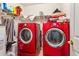 Bright laundry room features red washer and dryer set with overhead shelving and white walls at 60 Boardwalk Ave, Covington, GA 30016