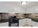 The kitchen featuring black countertops, tile backsplash, and white cabinets, oven and sink at 1501 Clairmont Rd # 1731, Decatur, GA 30033