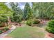 Extensive back yard with lush green grass, mature landscaping, and hardscape pathways to the deck at 2748 Hidden Falls Dr, Buford, GA 30519