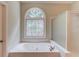 Bathroom with soaking tub and decorative mosaic-style window at 2748 Hidden Falls Dr, Buford, GA 30519