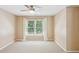 Bedroom with large window with white curtains, neutral carpeting, and ceiling fan at 5059 Belair Bluff Se Ct, Smyrna, GA 30126