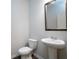 Clean bathroom features a white pedestal sink, toilet, decorative mirror, and wood-look flooring at 904 Sundown Pt, Villa Rica, GA 30180